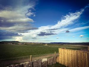 a field with a fence and a blue sky with clouds at Glengolly Getaways in Thurso