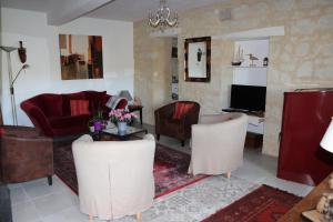 ein Wohnzimmer mit einem roten Sofa und Stühlen in der Unterkunft Chambres d'hôtes du Noisillet in Cinais