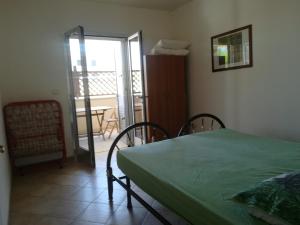 una camera con letto verde e balcone di House Pedone a Otranto