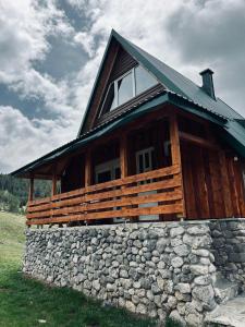 a large wooden cabin with a stone wall at Nomad Lodge Zminica in Žabljak