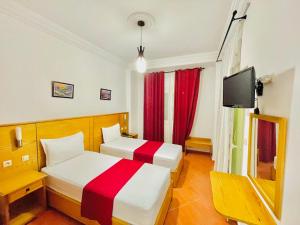 Habitación de hotel con 2 camas y TV en Sary's Hotel en M'diq