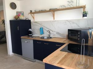 a kitchen with a sink and a microwave at T3 Proche des plages - Calme - Parking privé in Le Diamant