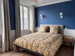 a bedroom with a bed with a blue wall at Appartement Richard Merrill, en plein centre, 4 pers in Sainte-Mère-Église