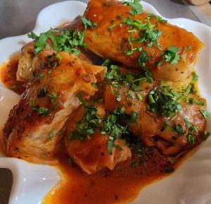 a plate of food with chicken covered in sauce at Chvibiani Guesthouse & Bar in Ushguli
