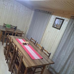 a wooden table in a room with two tables and chairs at Chvibiani Guesthouse & Bar in Ushguli