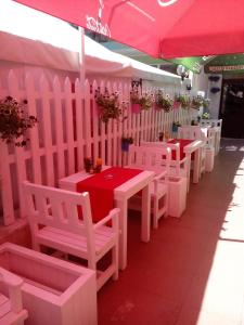 une rangée de tables et de chaises blanches sous une tente rose dans l'établissement Familia Fantastiko, à Kiten