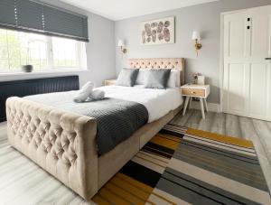 a bedroom with a large bed with a tufted headboard at Beautiful Newly Renovated House in Rainham Essex in Rainham