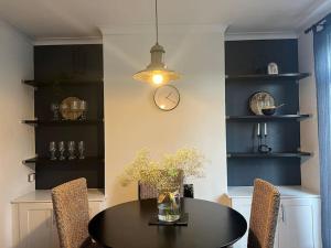 a dining room with a table and a clock on the wall at Cosy 3-Bedroom House 15mins to Olympic Village in Romford