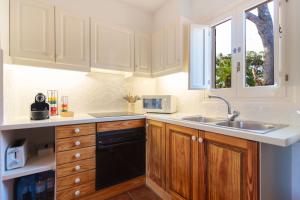a kitchen with wooden cabinets and a sink and a window at Aura de Mar - Dúplex boutique cerca de la playa in Son Xoriguer