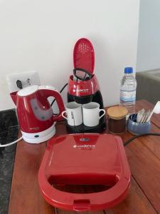 un mixeur rouge et des tasses sur une table en bois dans l'établissement Santomar Guest House, à Ilhabela