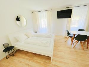 a white living room with a white couch and a table at StayHere Central City Studio 12 - contactless Self-Check-IN in Graz