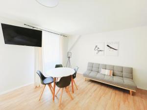 een woonkamer met een bank en een tafel en stoelen bij StayHere Central City Studio 12 - contactless Self-Check-IN in Graz