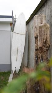 a surfboard leaning against a building next to a fence at Modernes Ferienhaus im Eidertal in Delve