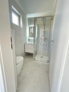 een witte badkamer met een douche en een toilet bij Put Lokvice 50 in Novalja