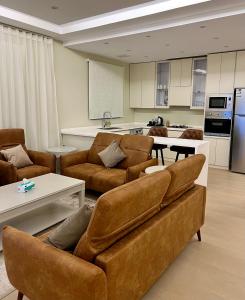 Il comprend un salon avec des meubles bruns et une cuisine. dans l'établissement شقة جديدة وفاخرة بالقرب من الحرم ., à Sīdī Ḩamzah