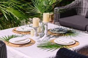 a table with a white table cloth with plates and candles at GREEN HILL Aparts with POOL & SCENIC VIEW in Gornji Orahovac