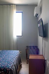 1 dormitorio con 1 cama, TV y ventana en Flat Residencial Meireles Fortaleza, en Fortaleza