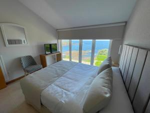 Schlafzimmer mit einem Bett und Meerblick in der Unterkunft Apartamentos Fontenla-Lanzada in Soutullo