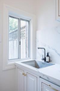 een witte keuken met een wastafel en een raam bij Cosy Federation Apartment Kirribilli 2 Bedroom #2 in Sydney