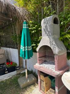an outdoor oven with an umbrella next to it at Mabel Rooms in Durrës