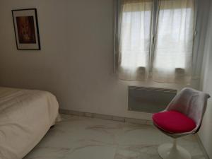 une chambre avec une chaise rouge devant une fenêtre dans l'établissement Appartement F2, à Bastia
