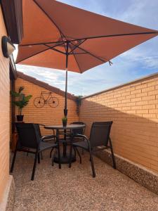 a table and chairs with an umbrella on a patio at Ático con terrazas en el caso antiguo in Huesca