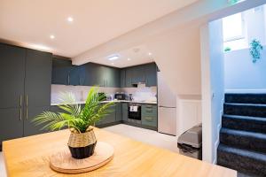 una cocina con armarios verdes y una mesa con una planta en The Large Group House -Sleeps 21, en Dublín