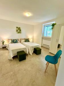 a bedroom with two beds and a blue chair at Villa Tra i Pini - Green & Relax in Castellana Grotte
