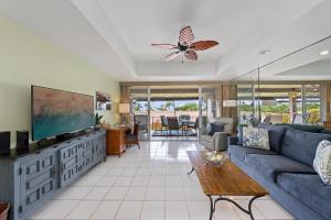 a living room with a blue couch and a flat screen tv at Eldorado L202 in Kahana