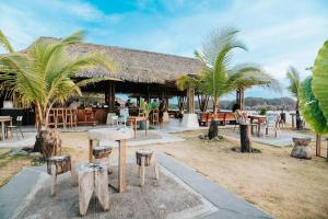 un complexe avec des tables, des chaises et des palmiers dans l'établissement Villa Ocean Pearl Venao, à Playa Venao