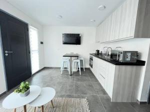 a kitchen with white cabinets and a table and chairs at Austral Apartment Regional in Valdivia