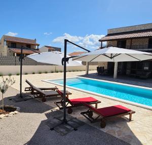 a pool with two lounge chairs and an umbrella at Vila Brod in Šibenik