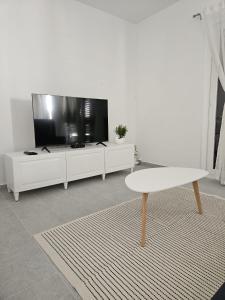 a white living room with a white table and a tv at Vila Brod in Šibenik