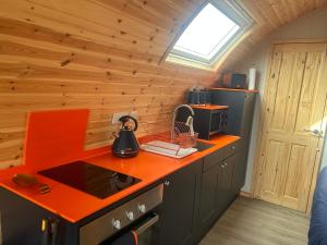 uma cozinha com um balcão laranja numa cabina em Kelly's Pod em Garynahine
