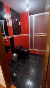 La salle de bains est pourvue de toilettes noires et de murs rouges. dans l'établissement Casa Hospedaje “YURAQ WASI”, à Huaraz