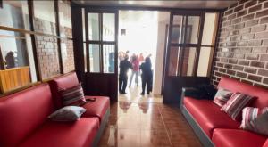 a living room with red couches and people walking in the doorway at Casa Hospedaje “YURAQ WASI” in Huaraz