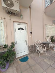 a white door with two chairs and a table at Cozy apartment in the center of Aighion Achaia - ground floor - ισόγειο στουντιο in Aigio