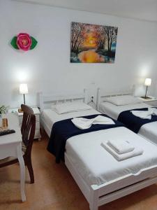 een slaapkamer met 2 bedden en een tafel en een schilderij bij Aggelis House in Sarandë