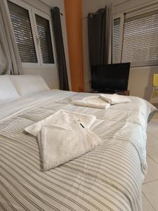 a bed with two towels sitting on top of it at Cozy apartment in the center of Aighion Achaia - ground floor - ισόγειο στουντιο in Aigio