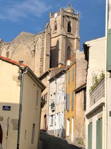 a church with a clock tower and some buildings at L'atelier in Capestang