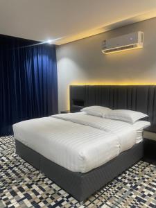 um quarto com uma grande cama branca com cortinas azuis em قمم بارك Qimam Park Hotel 4 em Abha