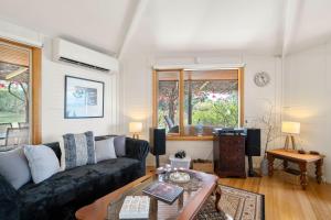 a living room with a black couch and a table at Blissful Birchs Bay - Gorgeous 3 Bedroom House in Woodbridge