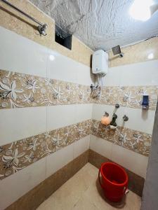 a shower with a red bucket in a bathroom at Spiritual Backpackers Hostel in Ujjain
