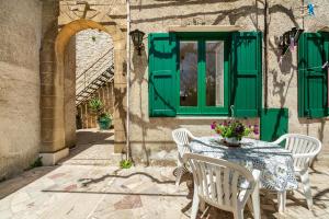un tavolo e delle sedie con una porta verde e una finestra di LEO APPARTAMENTI con vista panoramica a Erice