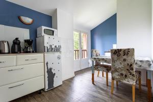 cocina con paredes azules, mesa y sillas en T2 Toulouse 40m2, Lit Queen Size, Climatisation, quartier sympa, Terrasse, en Toulouse