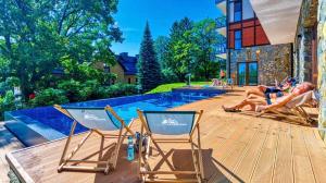 two people laying in chairs on a deck next to a pool at Apartament Silence Green Park - Strefa SPA in Szklarska Poręba