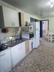 - une cuisine avec des appareils blancs, une table et des chaises dans l'établissement Casa Amarela, à Lages