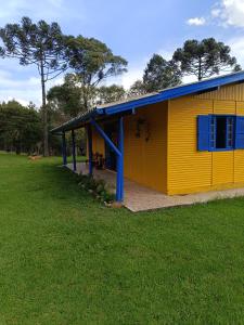 a yellow building with a blue roof on a field at Casa Amarela in Lages
