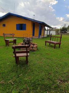 trzy ławki siedzące przed żółtym budynkiem w obiekcie Casa Amarela w mieście Lages