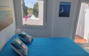 a bedroom with a blue bed with a window at ATLANTERRA PUEBLO in Zahara de los Atunes